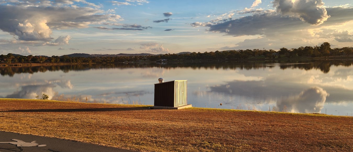A Hydro2050 cabinet on the shore of Lake Albert at dusk, the lake flat and clear behind it